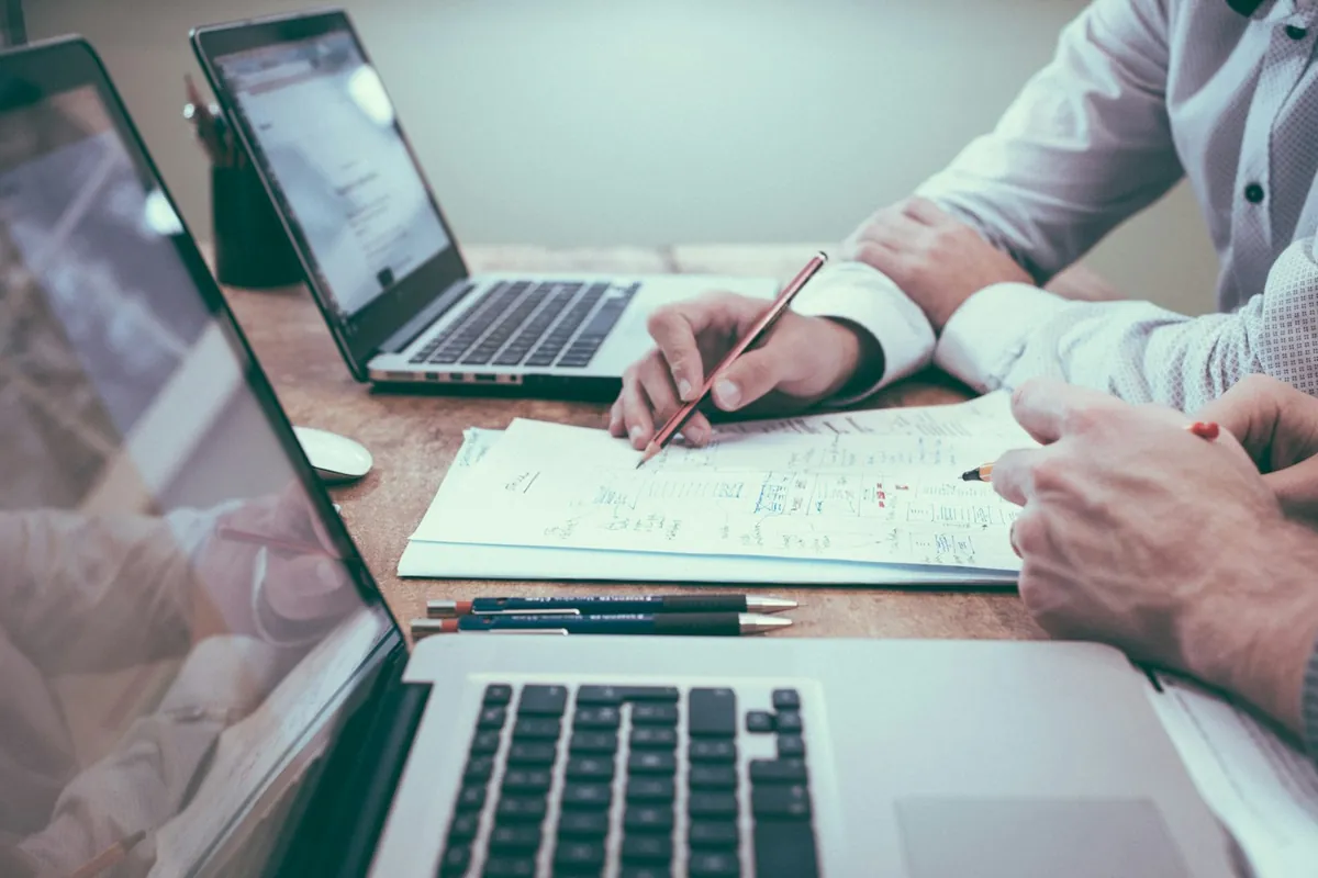 Person reviewing paperwork and charts beside a laptop